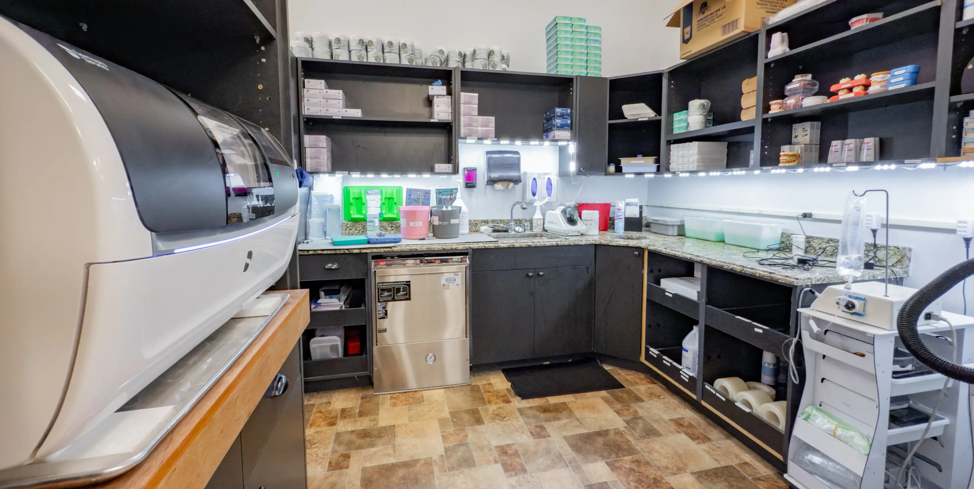 A small laboratory with cabinets, equipment, and supplies arranged neatly on shelves and countertops.